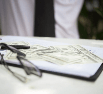 Cash on a desk beside glasses